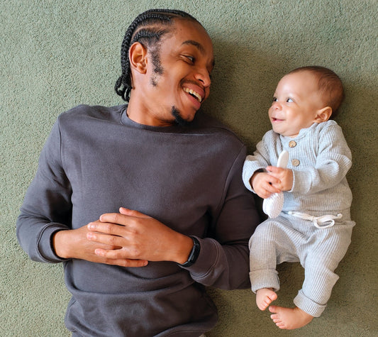 Image father and baby lying on floor smiling at each other